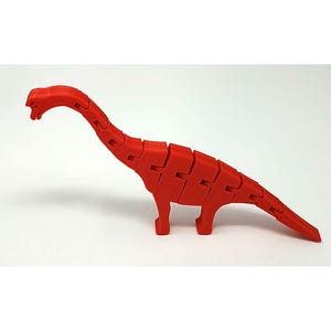 May include: A bright red articulated dinosaur figurine featuring a long neck and tail. The body is constructed from multiple segmented pieces connected by joints, allowing for flexible movement and posing of the neck, torso, and tail sections.