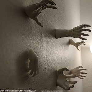 May include: Five white plaster hands are mounted on a white wall, reaching out with their fingers extended. The hands are arranged in a variety of positions, some with their palms facing forward and others with their palms facing backward. The hands are all the same size and shape, and they are all made of a smooth, white plaster.