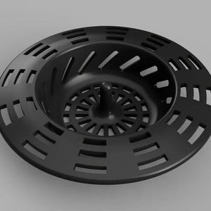 May include: A black sink strainer with a circular design. The strainer has a series of rectangular and angled cutouts around the outer edge. The center features a series of small holes and a central post.