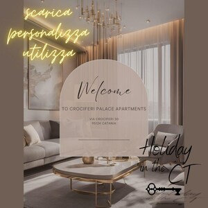 Può includere: Un cartello di benvenuto con il testo "Welcome to Crociferi Palace Apartments, Via Crociferi 30, 95124 Catania" in un soggiorno moderno con un divano, un tavolino da caffè e una sedia. Il testo "Holiday in the CT" è anche visibile nell'immagine.