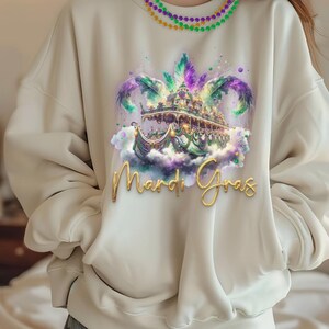 May include: A white sweatshirt featuring a colourful Mardi Gras float design and the text "Mardi Gras" in gold lettering.