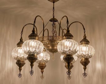 May include: An antique-style chandelier with six glass globe shades. The fixture has a brass finish with intricate filigree details. The glass shades have a ribbed texture, and the chandelier is suspended from the ceiling.