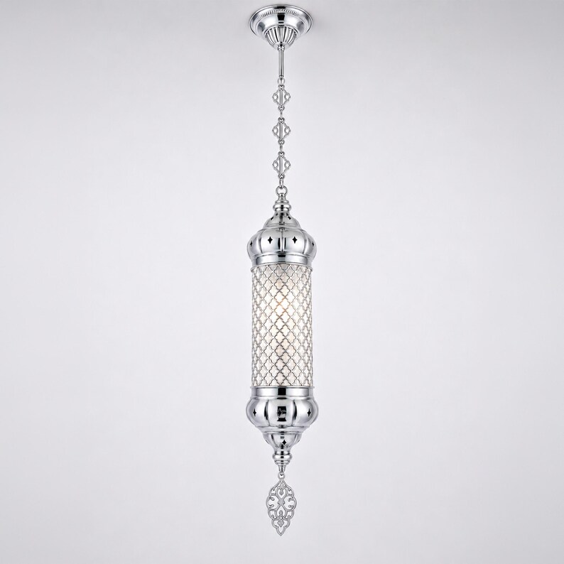 May include: A polished chrome pendant light fixture featuring a cylindrical body with an intricate lattice overlay. The lamp hangs from a matching chain and canopy, terminating in a decorative filigree finial at the bottom.
