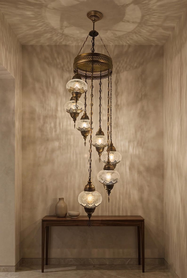 May include: An ornate, antique-style chandelier with multiple glass globes. The fixture has a bronze finish and is suspended from the ceiling. The glass globes have a textured pattern, and the light casts intricate shadows on the wall.