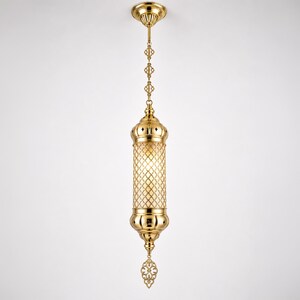 May include: A polished gold-tone metal pendant light fixture featuring a cylindrical body with an intricate lattice cutout pattern, suspended by a matching decorative chain and a circular ceiling canopy, with a pointed finial at the base.