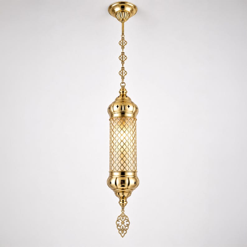 May include: A polished gold-tone metal pendant light fixture featuring a cylindrical body with an intricate lattice cutout pattern, suspended by a matching decorative chain and a circular ceiling canopy, with a pointed finial at the base.
