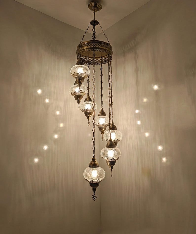 May include: An ornate, antique-style chandelier with multiple glass globes. The fixture has a bronze finish and features intricate metalwork. The clear glass globes are illuminated, casting a warm glow. The design is suitable for home decor.