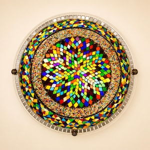 Puede incluir: Una lámpara de techo redonda con una pantalla de cristal en forma de cúpula cubierta por un vibrante mosaico de azulejos multicolores en forma de diamante. El diseño incluye un patrón de estrella central, un borde de cuentas y un borde de cristal.