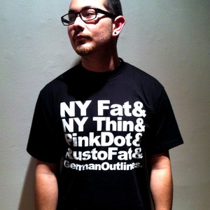 May include: A black t-shirt with white text that reads "NY Fat & NY Thin & PinkDot & RustoFat & GermanOutlines."