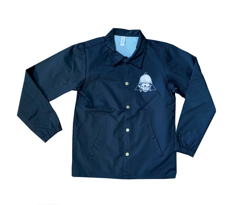 May include: A black coach jacket with a white skull and triangle design on the left chest. The jacket has a snap closure and two pockets.
