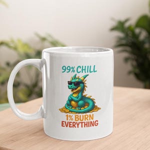 May include: White ceramic mug with a cartoon dragon wearing sunglasses. The dragon is teal and yellow, sitting on gold coins. Text on the mug reads "99% CHILL" and "1% BURN EVERYTHING."