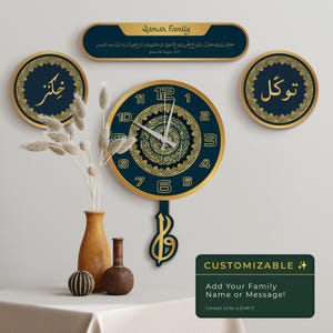 Puede incluir: Un reloj de pared decorativo azul marino y dorado con escritura árabe. El reloj está rodeado por dos adornos de pared circulares y un letrero rectangular. El texto "Qamar Family" es visible. El diámetro del reloj es de unos 30 cm.