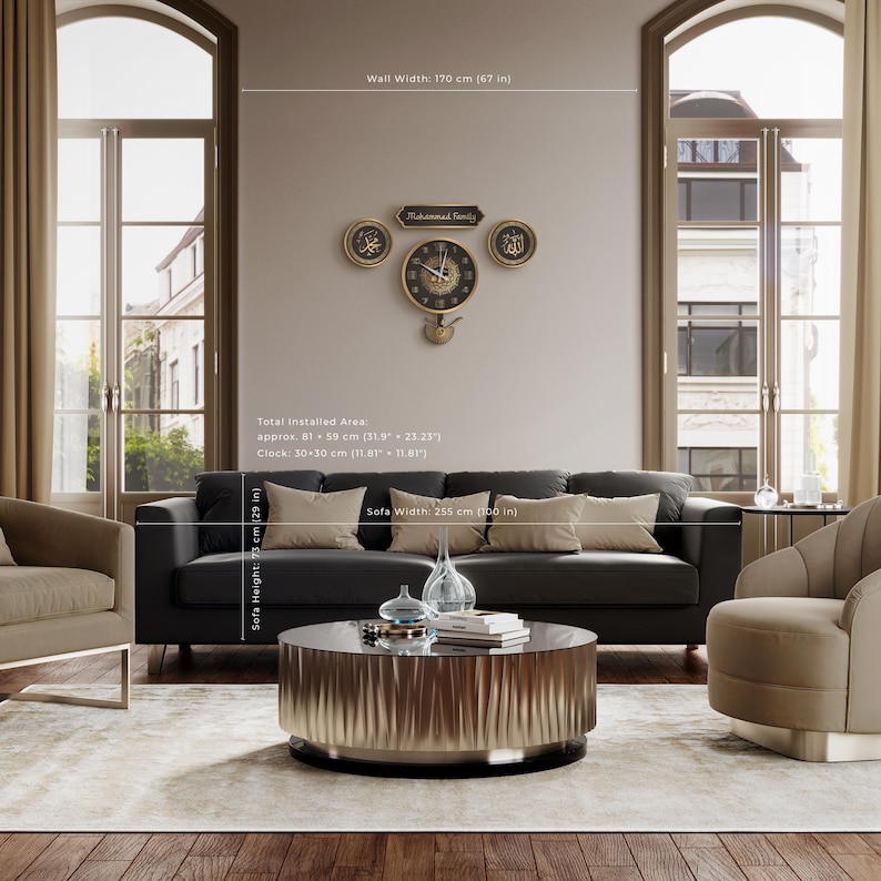 May include: A living room with a dark grey sofa, beige cushions, and a round coffee table. A wall clock with Arabic script and a family name is mounted above the sofa. The sofa is 255 cm wide, and the clock is 30 cm.