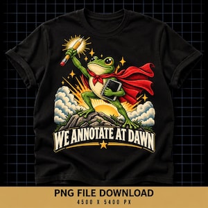 May include: A black t-shirt featuring a green frog wearing a red cape, holding a yellow pencil and a notebook. The frog stands on a rocky hill against a sunrise background with clouds and stars. The text WE ANNOTATE AT DAWN is printed below.