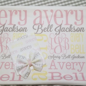 Puede incluir: Una manta de beb&eacute; blanca con el nombre Avery Bell Jackson impreso en rosa, amarillo y gris. La manta est&aacute; decorada con un monograma rosa y amarillo. Se incluye un peque&ntilde;o babero blanco con el nombre Avery impreso en rosa y amarillo.