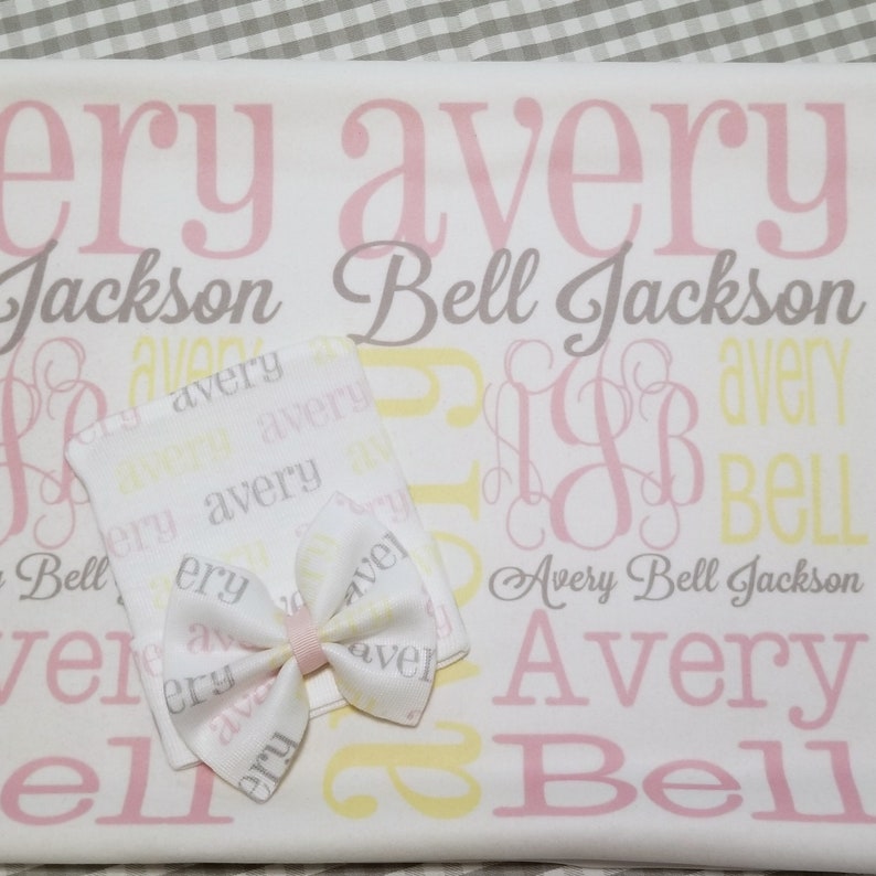 Puede incluir: Una manta de beb&eacute; blanca con el nombre Avery Bell Jackson impreso en rosa, amarillo y gris. La manta est&aacute; decorada con un monograma rosa y amarillo. Se incluye un peque&ntilde;o babero blanco con el nombre Avery impreso en rosa y amarillo.