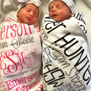 Puede incluir: Dos beb&eacute;s reci&eacute;n nacidos envueltos en mantas personalizadas. La manta de la ni&ntilde;a es rosa y blanca con el nombre "Emerson Mignon Steere" impreso en rosa y negro. La manta del ni&ntilde;o es blanca y azul con el name "Hunter William Steere" impreso en negro y gris.