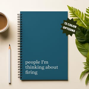 May include: A teal spiral-bound notebook with the text "people I'm thinking about firing" in white. A white pencil and a cup of coffee are on the left. A green starburst graphic with "12 COLOR OPTIONS" is on the right.
