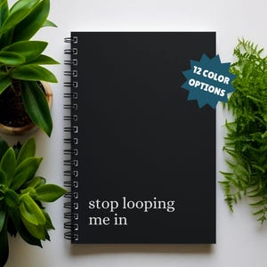 May include: Black spiral bound notebook with the text "stop looping me in" in white lettering. The notebook has a blue starburst sticker with the text "12 color options".