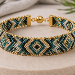 May include: A beaded bracelet featuring a geometric diamond pattern in shades of teal, black, white, and metallic gold. The bracelet is constructed from small uniform beads and is finished with gold-toned metal end caps and a spherical magnetic clasp.