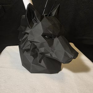May include: A matte black, geometric wolf head desk organizer featuring a faceted, low-poly design. The hollow interior holds a white marker and two thin black tools, providing a functional storage solution for various office or art supplies.