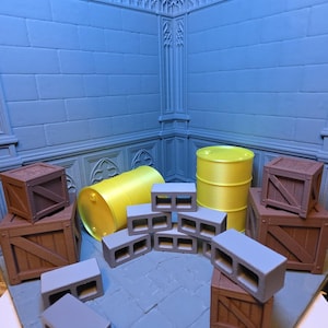 May include: A miniature diorama set featuring a light blue stone-textured wall corner, two bright yellow barrels, several brown wooden crates with diagonal bracing, and multiple grey cinder blocks arranged on a stone-patterned floor base.