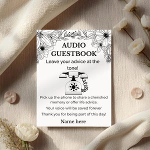 以下が含まれることがあります： 「AUDIO GUESTBOOK」の文字と花の模様が入った白いカード。アドバイスを残すための指示と、ヴィンテージ電話のグラフィックが含まれています。テキストは「Leave your advice at the tone!」と「Name here」です。