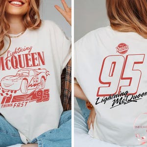 K&ouml;nnte beinhalten: Wei&szlig;es T-Shirt mit einer roten Grafik von Lightning McQueen aus dem Film Cars. Die Grafik enth&auml;lt den Text "Lightning McQueen", "Think Fast" und die Nummer "95".
