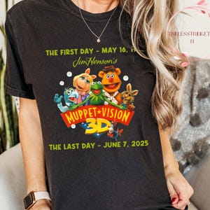 May include: Black t-shirt featuring a colorful graphic of Muppet characters with the text "Muppet Vision 3D." The shirt also includes the text "The First Day - May 16" and "The Last Day - June 7, 2025."