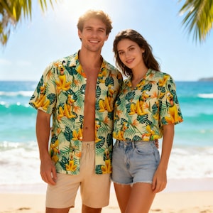 Może przedstawiać: Dwie osoby ubrane w pasujące koszule z krótkim rękawem zapinane na guziki z żółto-zielonym tropikalnym nadrukiem z Pluto. Koszule są połączone z beżowymi szortami i dżinsowymi szortami. Tło obejmuje plażę, ocean i liście palmowe.