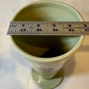 Puede incluir: Un c&aacute;liz de cer&aacute;mica verde p&aacute;lido con la parte superior ensanchada y una base de pedestal. El borde mide aproximadamente 7,6 cm de di&aacute;metro. Se coloca una regla sobre la parte superior del c&aacute;liz para medir.