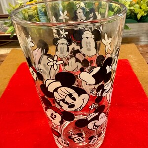 Puede incluir: Vasos de vidrio transparente con un patr&oacute;n repetido de personajes de Mickey y Minnie Mouse en negro, blanco y rojo. Los vasos son cil&iacute;ndricos y adecuados para bebidas. El dise&ntilde;o incluye acentos florales.