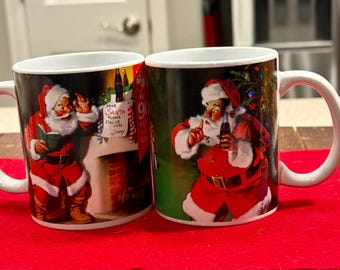 Two collectible ceramic mugs celebrating "90 Years of Coca-Cola Santa".