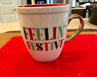 The "Feelin Festive" coffee mug with the gold handle by  Sleigh Bell