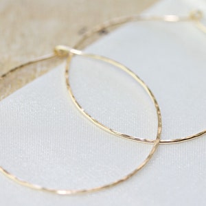 May include: A pair of gold hoop earrings with a hammered texture. The earrings are simple and elegant.