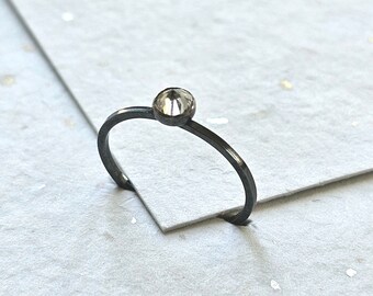 May include: A simple silver ring with a clear faceted gemstone.