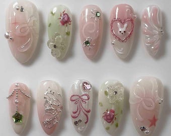 Presse lapin pastel fait main sur les ongles | Rubans roses, fleurs et breloques coeur | Ongles en amande pour de douces vibrations romantiques