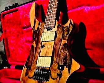 May include: A custom electric guitar with a unique wood grain pattern in shades of brown and tan. The guitar features black hardware, cream-colored pickups, and a rosewood fretboard. It rests against a red guitar case.