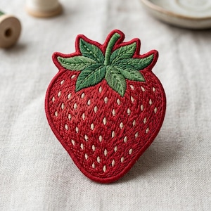 May include: Embroidered strawberry patch with a vibrant red body and green leaves. The patch features white seed details and a red border. This decorative patch can be sewn or ironed onto clothing or accessories.