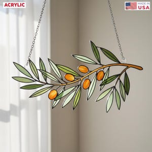 May include: Acrylic olive branch decoration with green leaves and orange olives, suspended by a silver chain. The product is labeled "Made in USA" and "Acrylic".