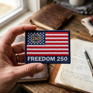 May include: A rectangular patch featuring the American flag design with red and white stripes and a blue field of stars. The text "250" is inside a gold circle in the upper left corner, and the words "FREEDOM 250" are at the bottom.