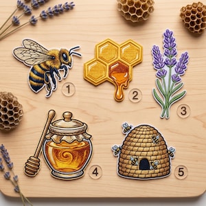 May include: A collection of embroidered patches featuring bee-related designs. Includes a detailed bee, a honeycomb with dripping honey, lavender sprigs, a honey pot with a dipper, and a beehive with bees. The patches are on a light wood surface.