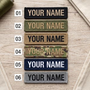 May include: A selection of six rectangular patches with the text "YOUR NAME" embroidered in various colors. The patches are black, olive green, tan, camouflage, navy blue, and gray. The patches are displayed on a light wood surface.