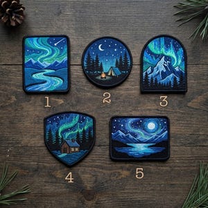 May include: Five embroidered patches featuring night landscapes with aurora borealis, mountains, forests, a tent with a campfire, and a cabin. Each patch is numbered one through five and displays detailed blue and green thread work.