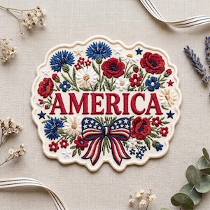 May include: Embroidered patch with the word "AMERICA" in red, surrounded by red poppies, blue cornflowers, white daisies, and a patriotic bow. The patch has a scalloped edge and star accents, perfect for patriotic crafts.