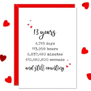 May include: A white greeting card with a red border and the text "13 years" in elegant script. The card includes the number of days, hours, minutes, and seconds, with the phrase "and still counting". Red heart illustrations are scattered around the card.