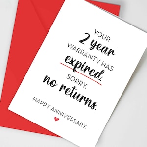 May include: A white greeting card with black text that reads: YOUR 2 year WARRANTY HAS expired. SORRY, no returns. HAPPY ANNIVERSARY. There is a red horizontal line under the word expired and a small red heart icon below the text, paired with a red envelope.