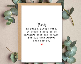 Puede incluir: Una tarjeta de felicitación blanca con la palabra "Gracias" en escritura cursiva. La tarjeta contiene un mensaje sincero en texto negro y un pequeño corazón rojo. La tarjeta está sobre un fondo neutro con follaje verde.