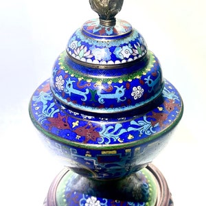 May include: A blue and gold cloisonn&eacute; incense burner with a floral design and a dragon motif. The burner is on a wooden stand.