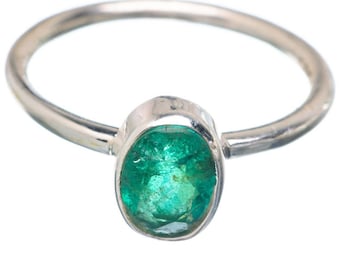May include: A silver ring featuring an oval-cut, vibrant green emerald gemstone. The emerald is set in a polished silver band, creating a classic and elegant design. The ring is shown against a white background, highlighting the gemstone's color.